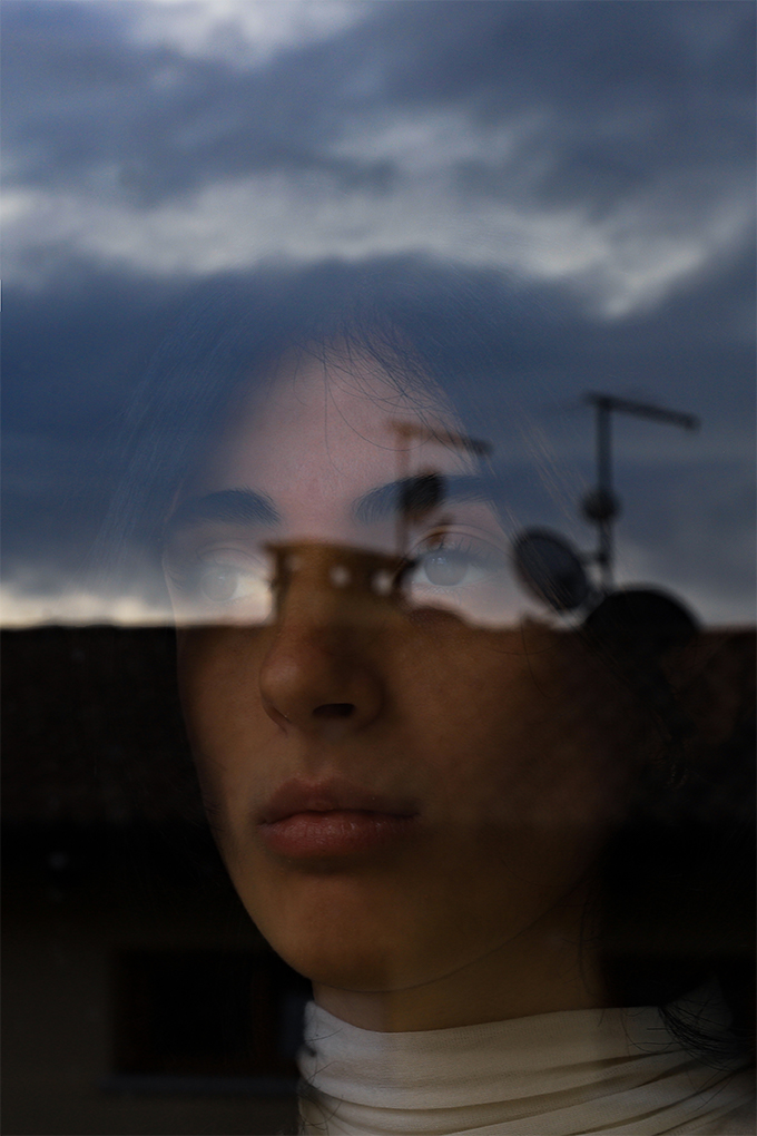 Iridescent, Martina Dalla Vecchia
Fotografia di una ragazza riflesso nella finestra al tramonto