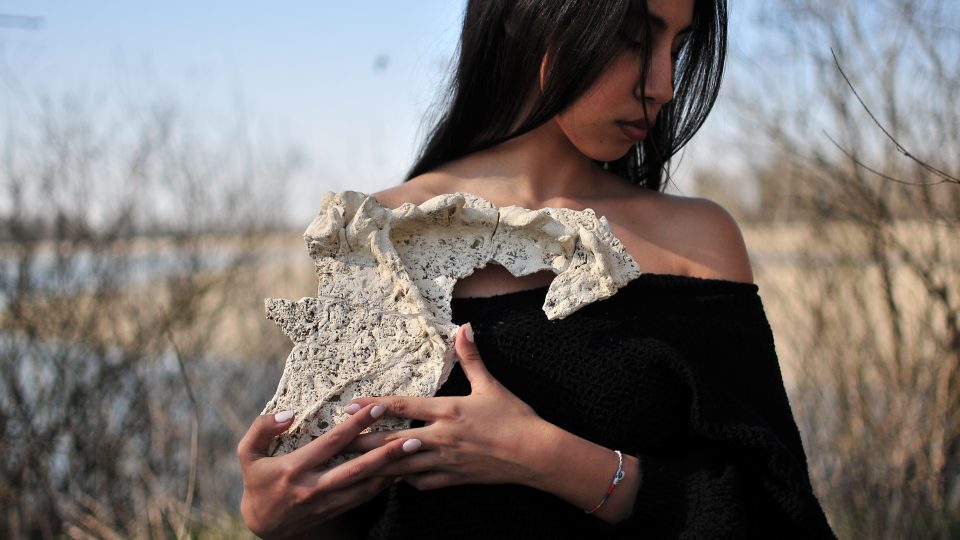 L'artista tiene in mano l'opera "Le mie crepe sono riemerse" fatta con gesso, metallo.